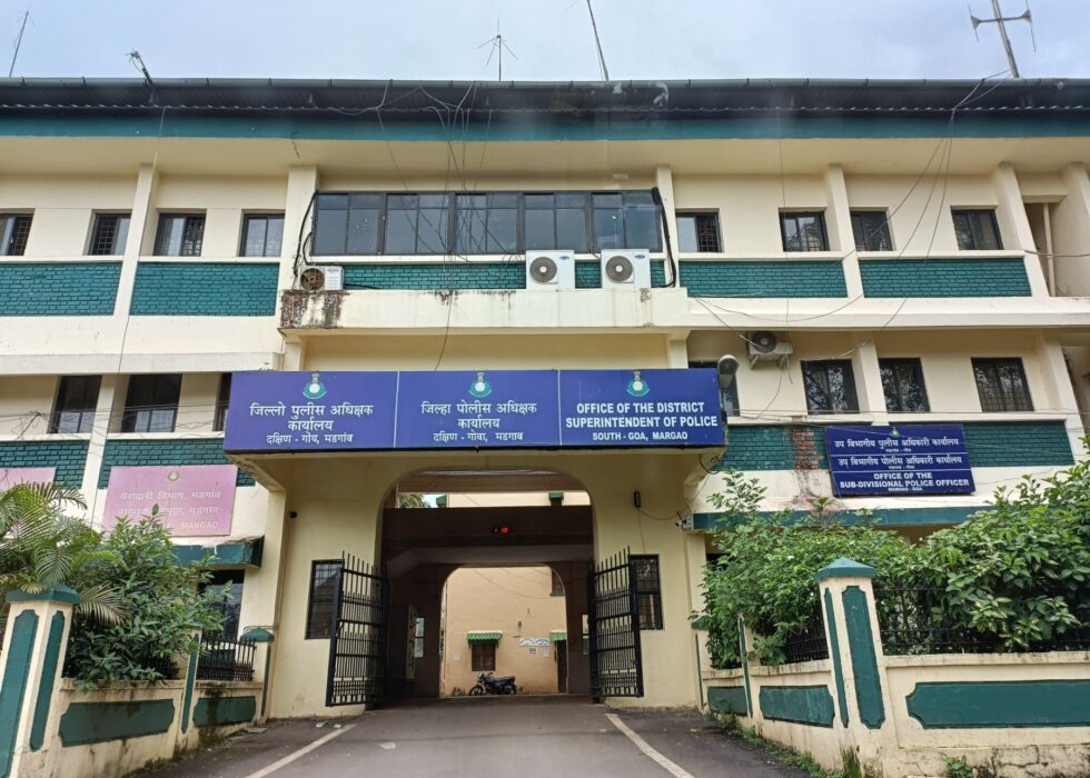 The image shows the Office of the District Superintendent of Police in South Goa, Margao, a multi-story cream and green building with a gated archway entry
