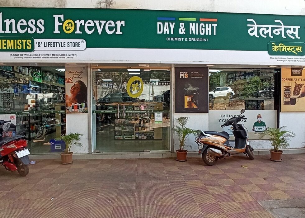 The image shows the Wellness Forever Pharmacy storefront located at Socorro Panchayat, Porvorim, Goa. The address visible on the sign right below the Hindi text explicitly lists Shop No. 23, Ground Floor of Sansha's Lajoy.